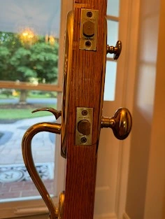 Residential lock installation of an elegant brass handle set on a wooden door by AA Locksmith Near Me LLC.