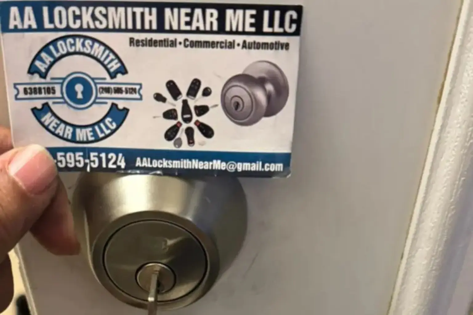 A technician holds an AA Locksmith Near Me LLC business card above a newly installed secure deadbolt lock and lever handle with keys inserted, illustrating a reliable locksmith service